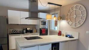 A modern kitchen with white cabinetry, a central island, a built-in oven, and pendant lighting. - Charming duplex 4 to 6 persons Risoul 1850 (Risoul)
