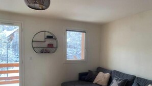 A living room with a grey sofa, a round coffee table, and a wall-mounted shelf. - Charming duplex 4 to 6 persons Risoul 1850 (Risoul)