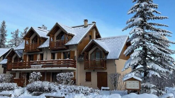 A chalet-style building with a balcony, surrounded by snow-covered trees. - Charming duplex 4 to 6 persons Risoul 1850 (Risoul)
