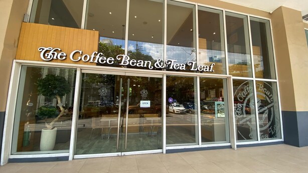 A coffee shop named "The Coffee Bean & Tea Leaf" with large glass windows and a wooden signboard.