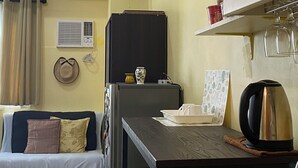 A compact kitchen with a refrigerator, a coffee maker, and a dining table.