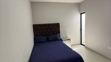 A bedroom with a bed, a nightstand, an air conditioning unit, and a ceiling light.