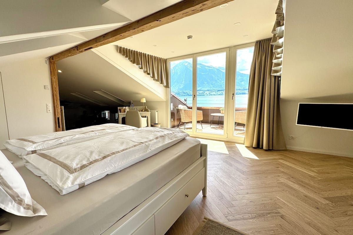 A bedroom with a bed, a desk, a chair, and a TV.