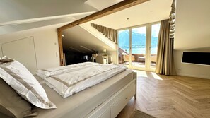 A bedroom with a bed, a desk, a chair, and a TV. - Boutique Hotel Niesenblick Self Check In (Oberhofen am Thunersee)