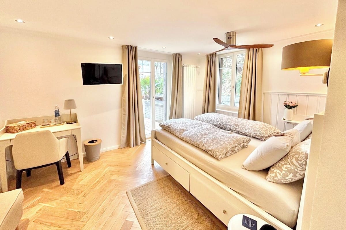 A bedroom with a bed, desk, chair, and a TV.