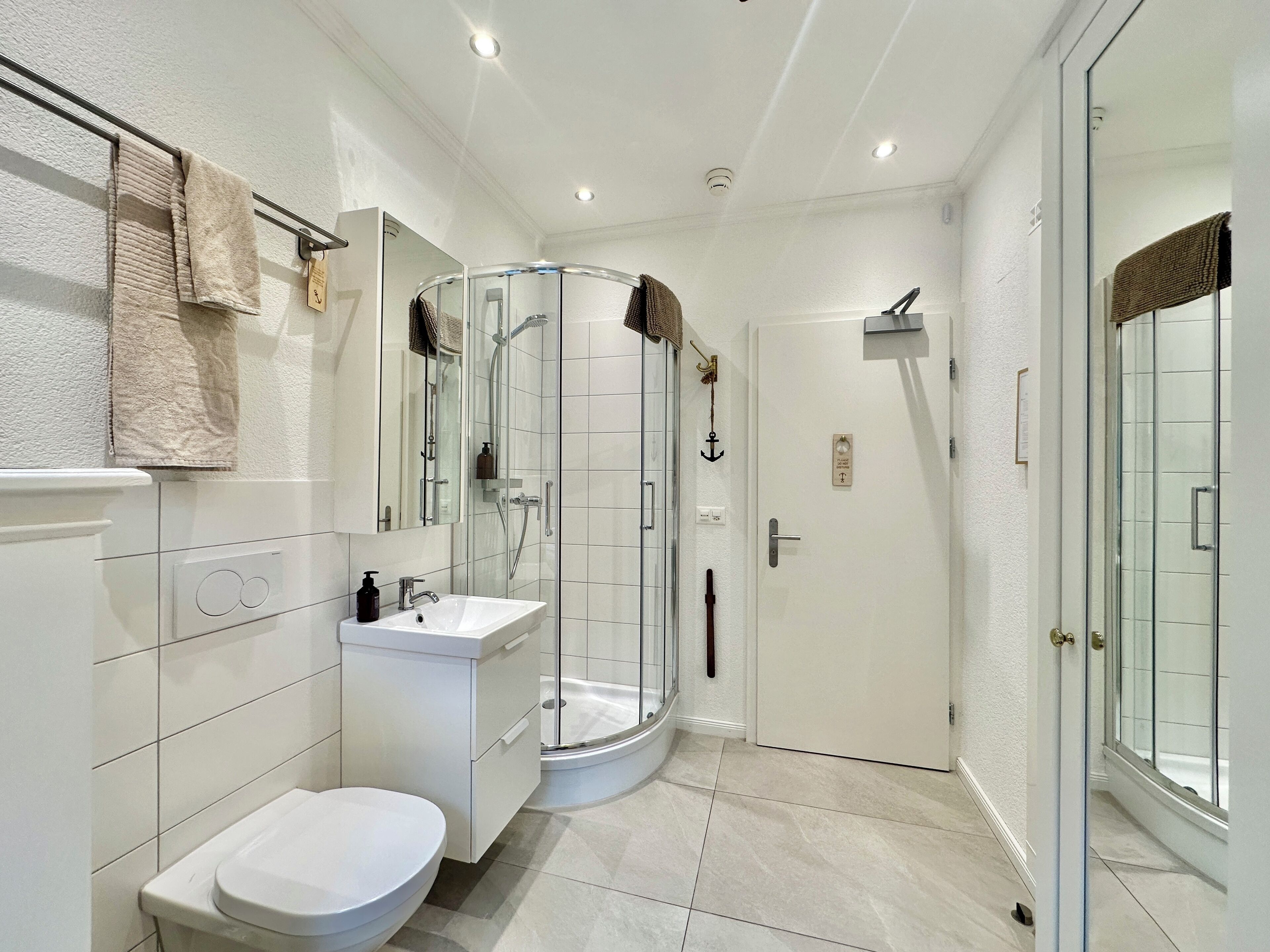 A modern bathroom with a glass-enclosed shower, a white sink, and a toilet.