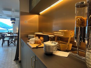 A modern kitchen with a long counter, wooden bread baskets, and a coffee machine. - Boutique Hotel Niesenblick Self Check In (Oberhofen am Thunersee)
