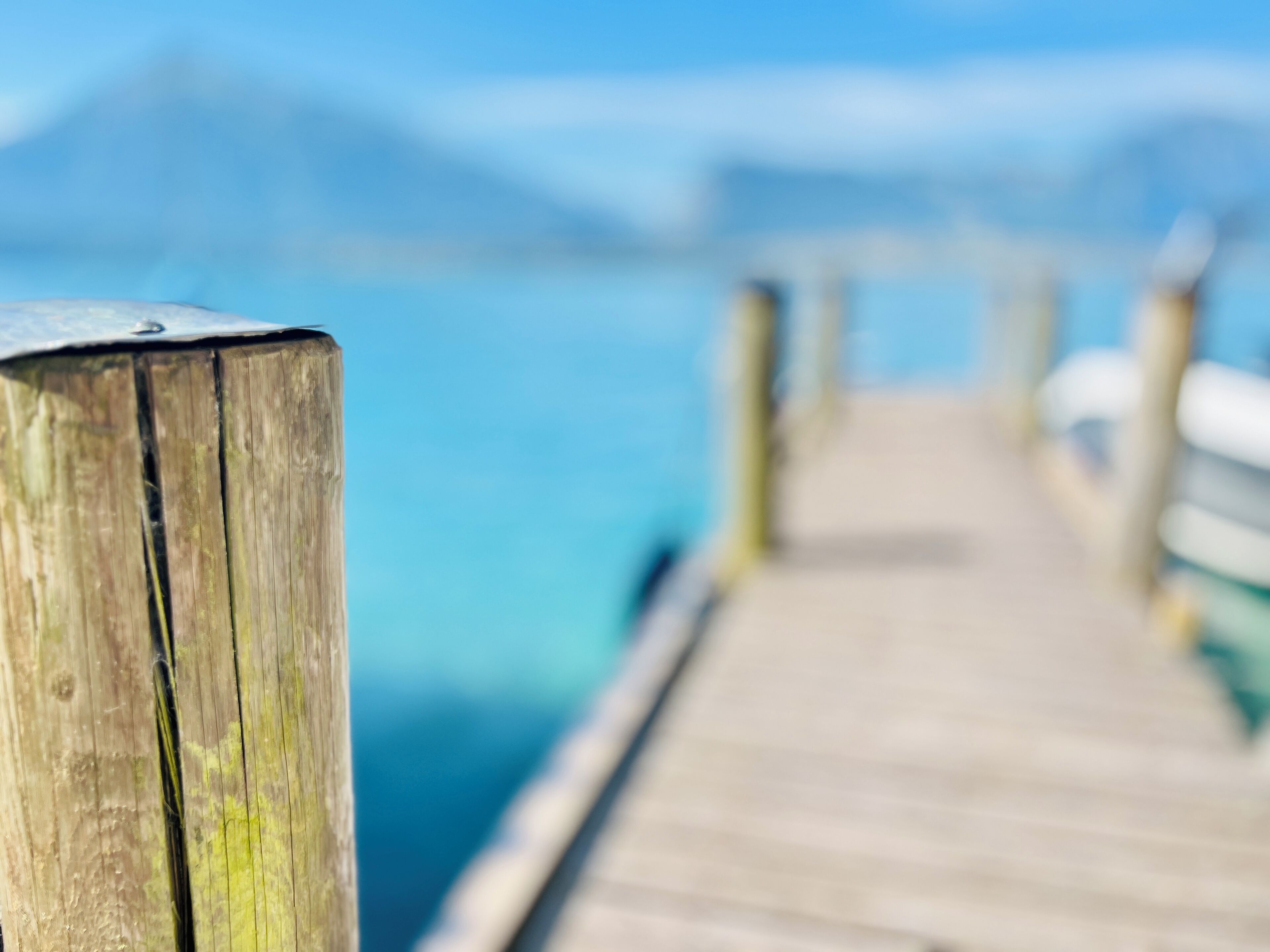 A wooden pier extending into a body of water with a mountain in the background.