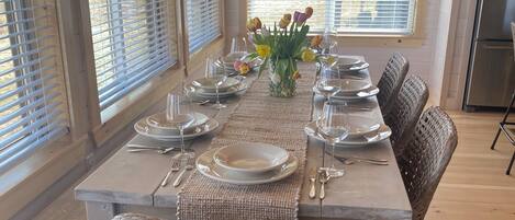A dining area with a wooden table set for six, surrounded by wicker chairs.