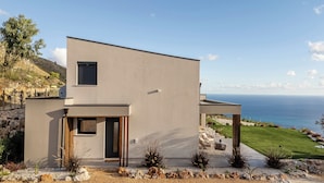 Een modern huis met een plat dak, een klein balkon en uitzicht op zee.