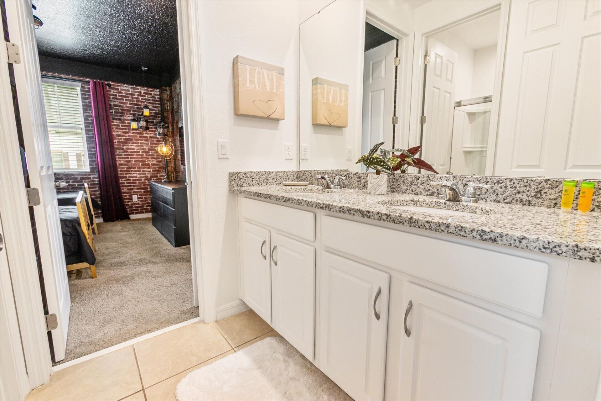 A modern kitchen with white cabinets, granite countertops, and a large mirror.
