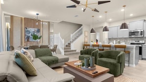 A modern living room with a sofa, armchairs, a coffee table, and a staircase leading to a kitchen area. - Last Minute Disney Getaway! Private Pool & Game Room. Book Now! #121741 (Orlando)