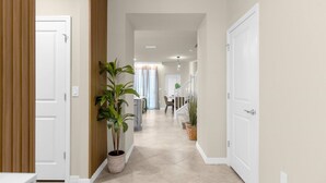 A hallway with white doors, wooden paneling, and potted plants. - Last Minute Disney Getaway! Private Pool & Game Room. Book Now! #121741 (Orlando)
