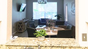 Una cocina con encimera de granito, un lavamanos y una zona de comedor con mesa y sillas.