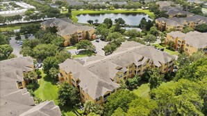 Zona residencial con varios edificios de apartamentos, un estanque central y abundante vegetación.