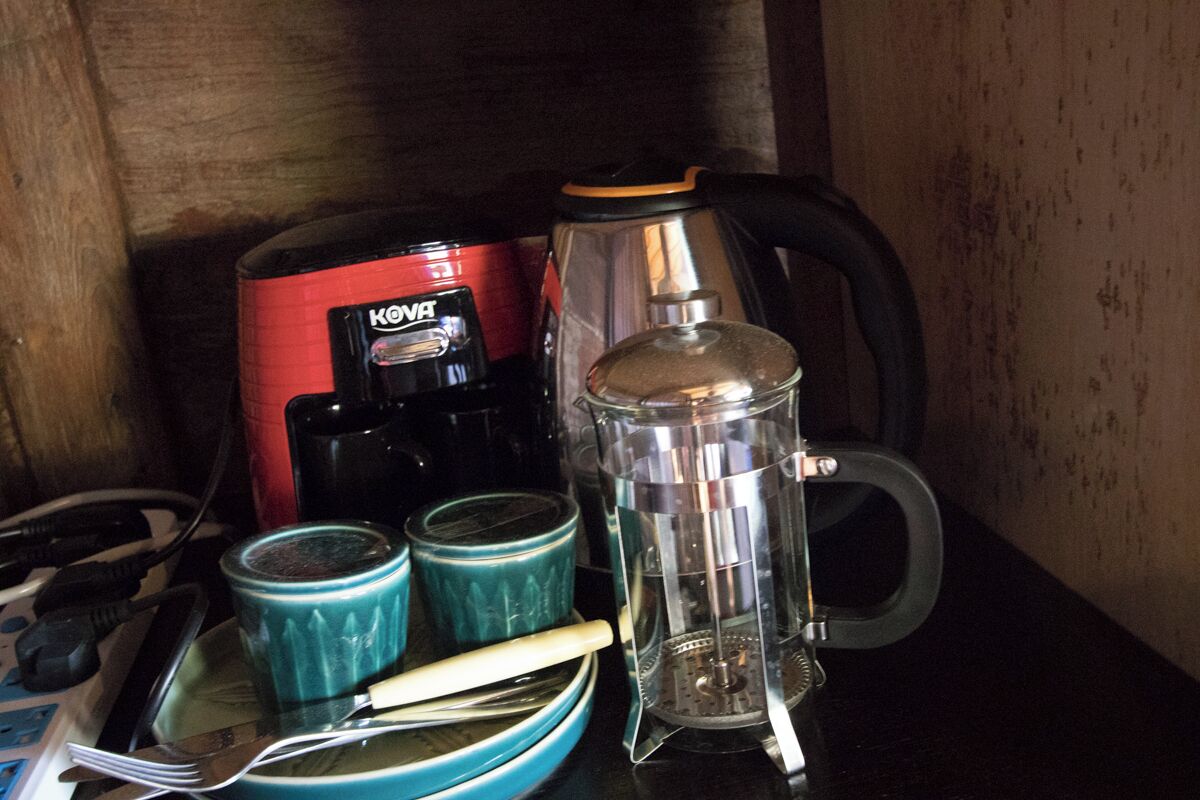 A kitchen area with a coffee maker, a blender, and two blue mugs on a table.