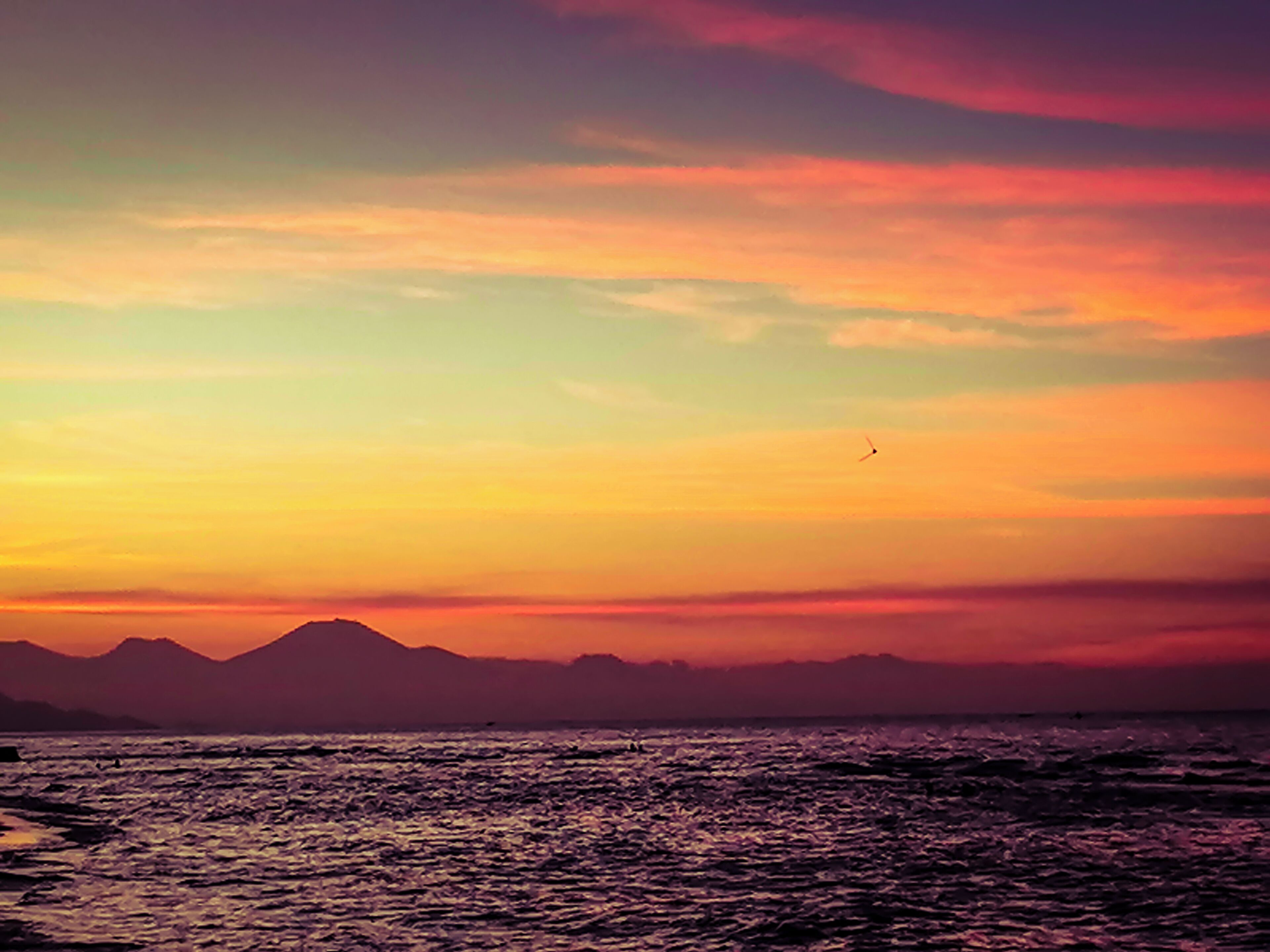 A sunset over a body of water with mountains in the background.