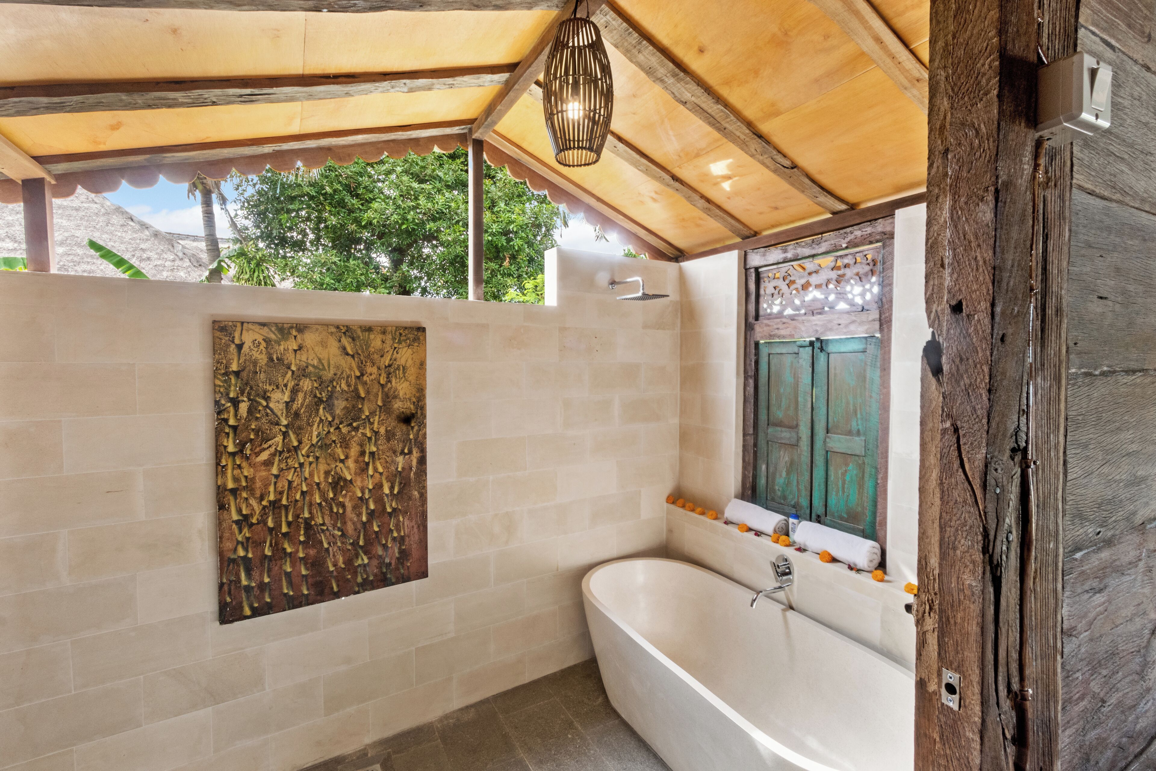 Un baño con una bañera independiente, techo de madera y un adorno mural.