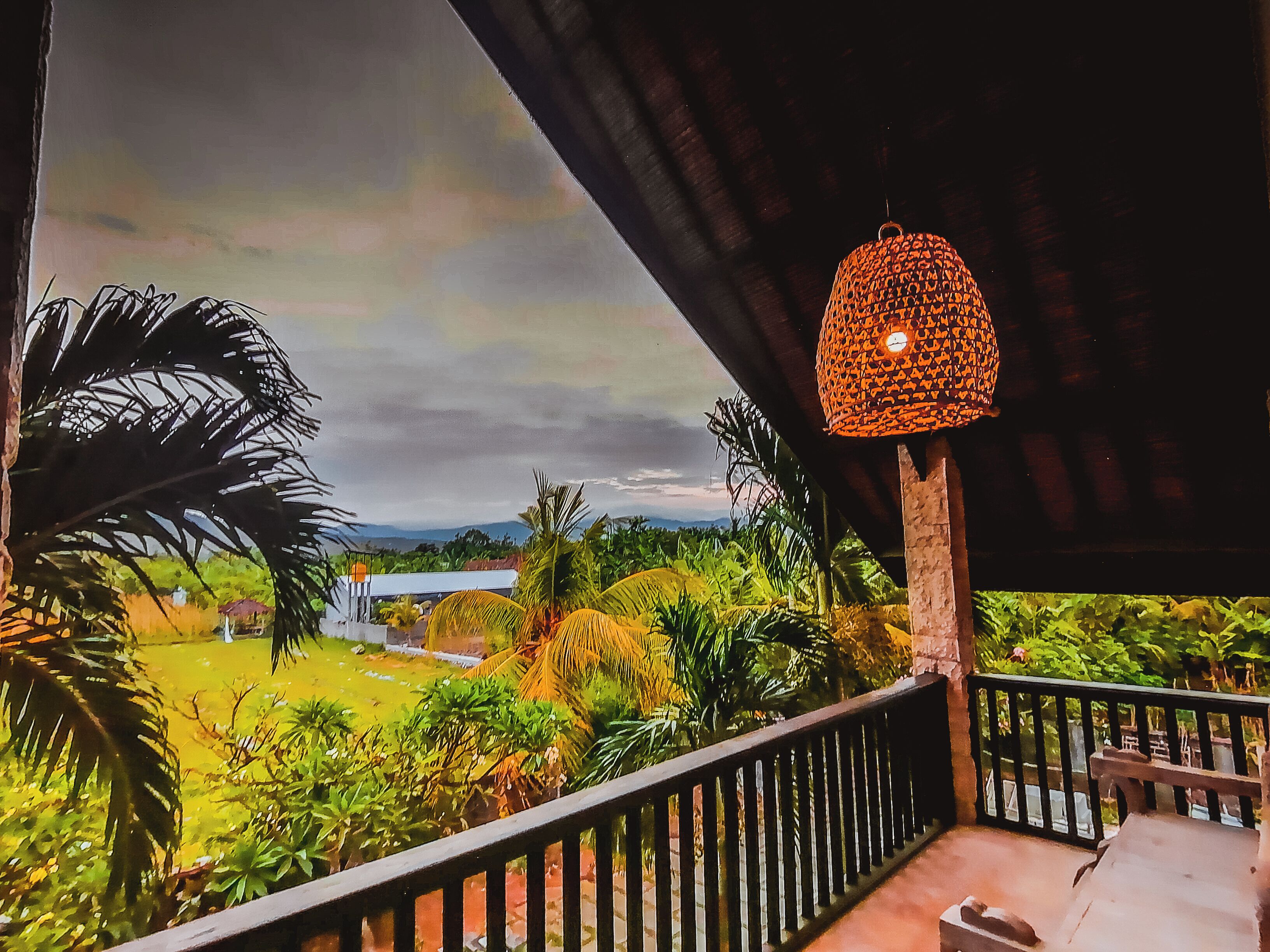 A balcony with a view of a garden and mountains.