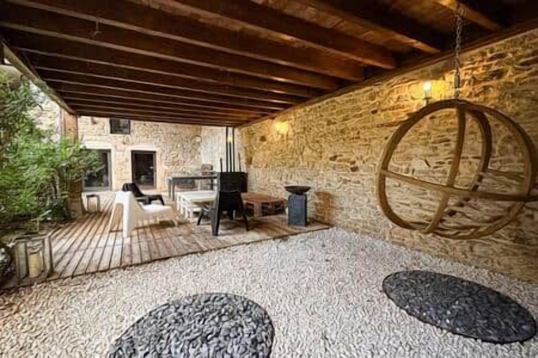 Eine Außenpatio mit Steinmauern, einer hängenden, kugelförmigen Leuchte und einer Holzbalkendecke.