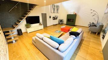 A modern living room with a staircase, a large sofa, a coffee table, and a fireplace.