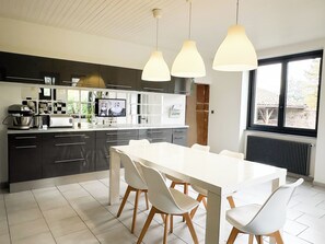 Una cucina moderna con un'isola grande, sedie bianche e lampade a sospensione.