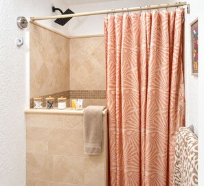 A bathroom with a shower curtain, a towel rack, and toiletries on a shelf.