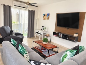Una sala de estar con sofá, mesa de centro, televisor y ventilador de techo.