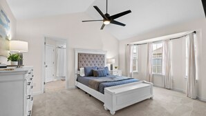 A bedroom with a large bed, a ceiling fan, and a view of the outside through a window. - Greenway Getaway: Central to NWA & on the Razorback Greenway (Rogers)