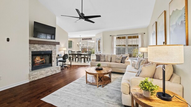 A spacious living room with a fireplace, a ceiling fan, a dining area, and a sofa. - Greenway Getaway: Central to NWA & on the Razorback Greenway (Rogers)