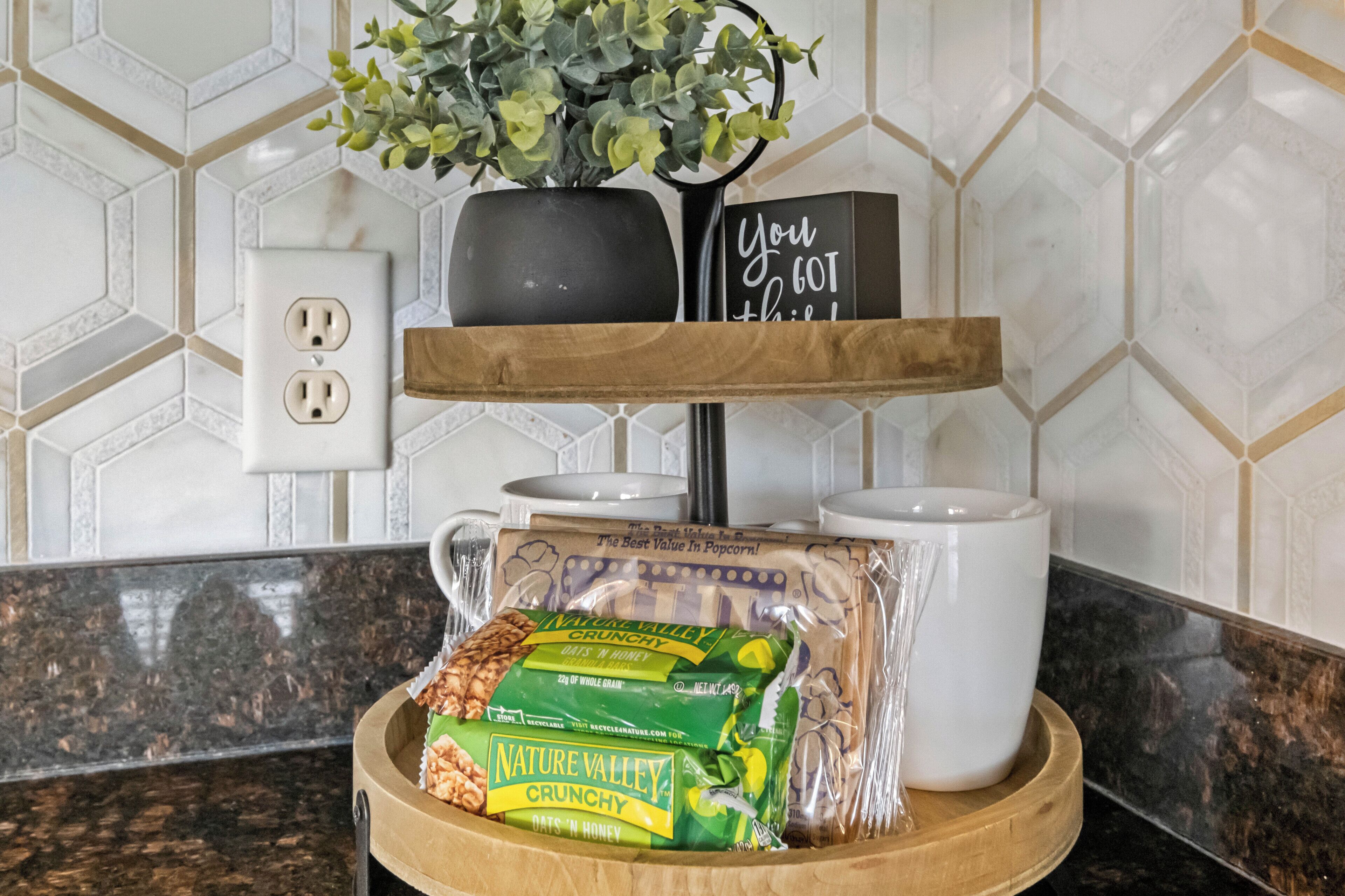 A kitchen counter with a wooden tray holding a package of Nature Valley Oats 'n Honey, a white mug, and a black sign with the text "You GOT this!"