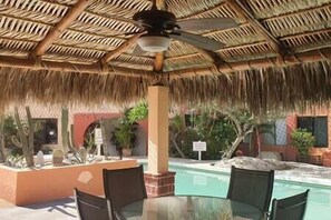 Un espace extérieur abrité comprenant une piscine, des chaises et des plantes en pot.