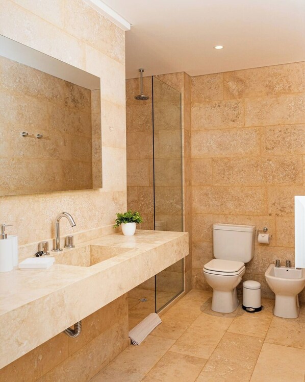 Une salle de bain moderne avec un grand miroir, deux lavabos, des toilettes et un bidet.