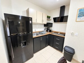 A modern kitchen with a black refrigerator, a coffee maker, and a microwave. - Chic Cabo Gateaway Walkable to Beach & Downtown Fun (Cabo San Lucas)