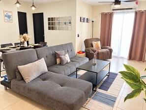 A modern living room with a grey sectional sofa, a coffee table, and a dining area with a table set for two.
