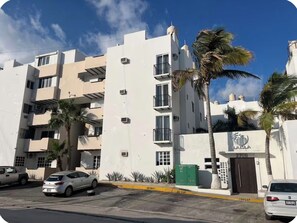 A multi-story residential building with balconies, a gated entrance, and parked cars. - Chic Cabo Gateaway Walkable to Beach & Downtown Fun (Cabo San Lucas)