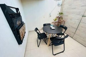 A small patio with a round table and four chairs, a small cabinet, and a potted plant.