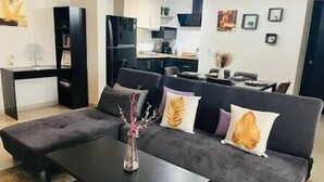 A modern living room with a dark grey sofa, a coffee table, and a vase with branches. - Chic Cabo Gateaway Walkable to Beach & Downtown Fun (Cabo San Lucas)