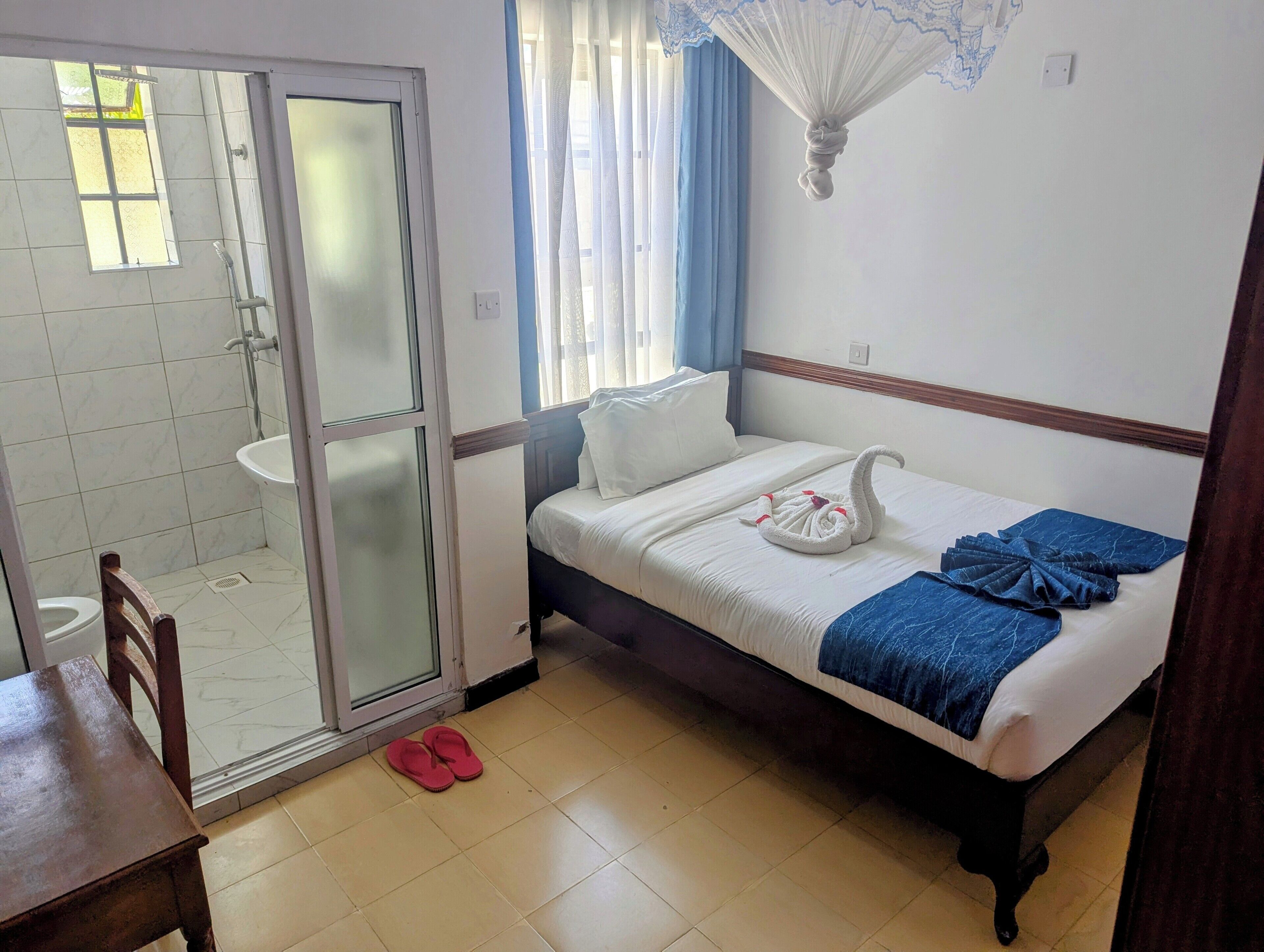 Une chambre d’hôtel avec un lit, un espace douche et une fenêtre avec des rideaux.