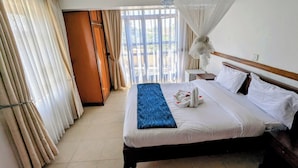 Een hotelkamer met een bed, gordijnen, een nachtkastje en een raam met uitzicht.