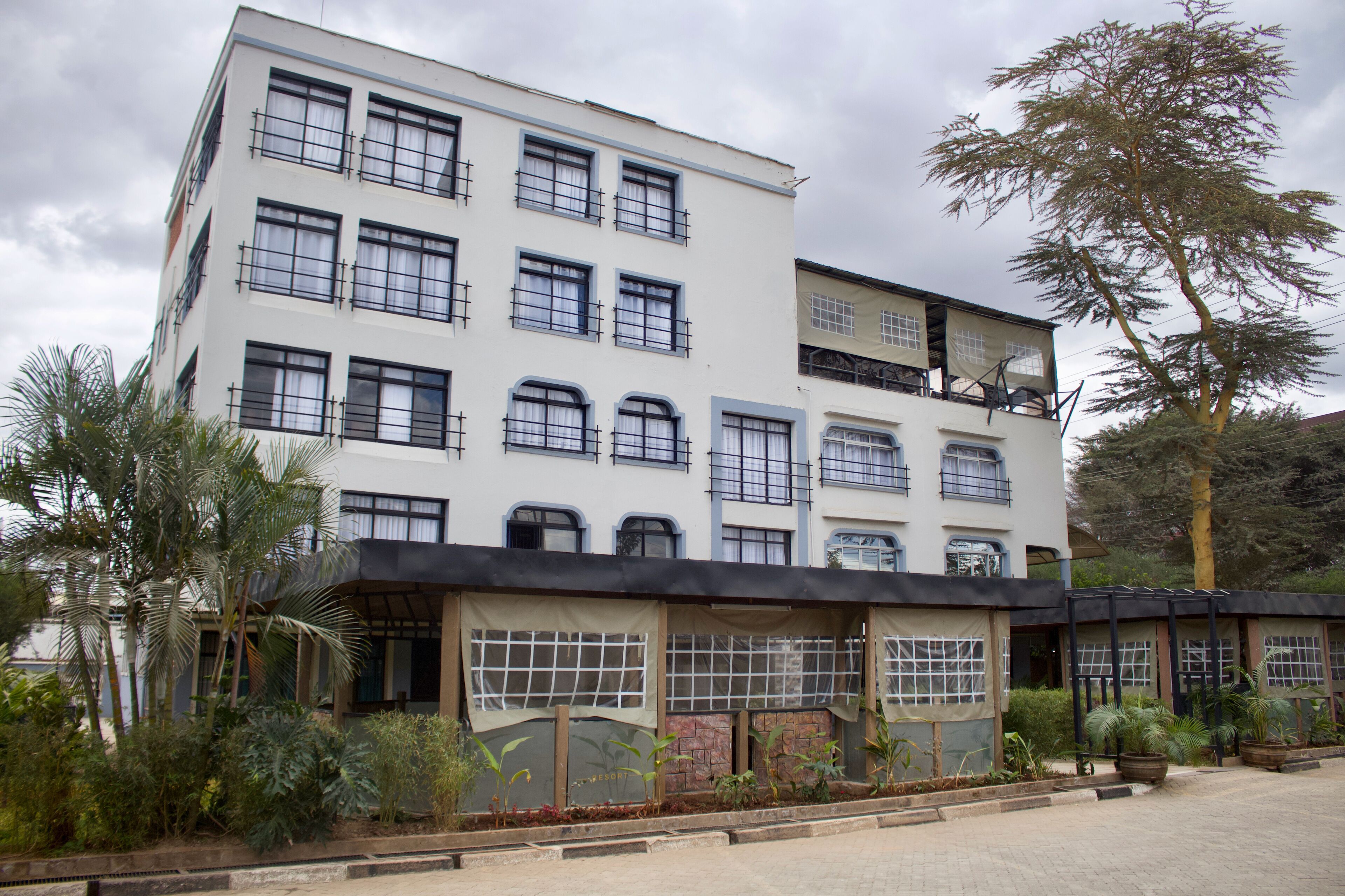 A multi-story building with a flat roof, large windows, and a balcony on the upper floor.