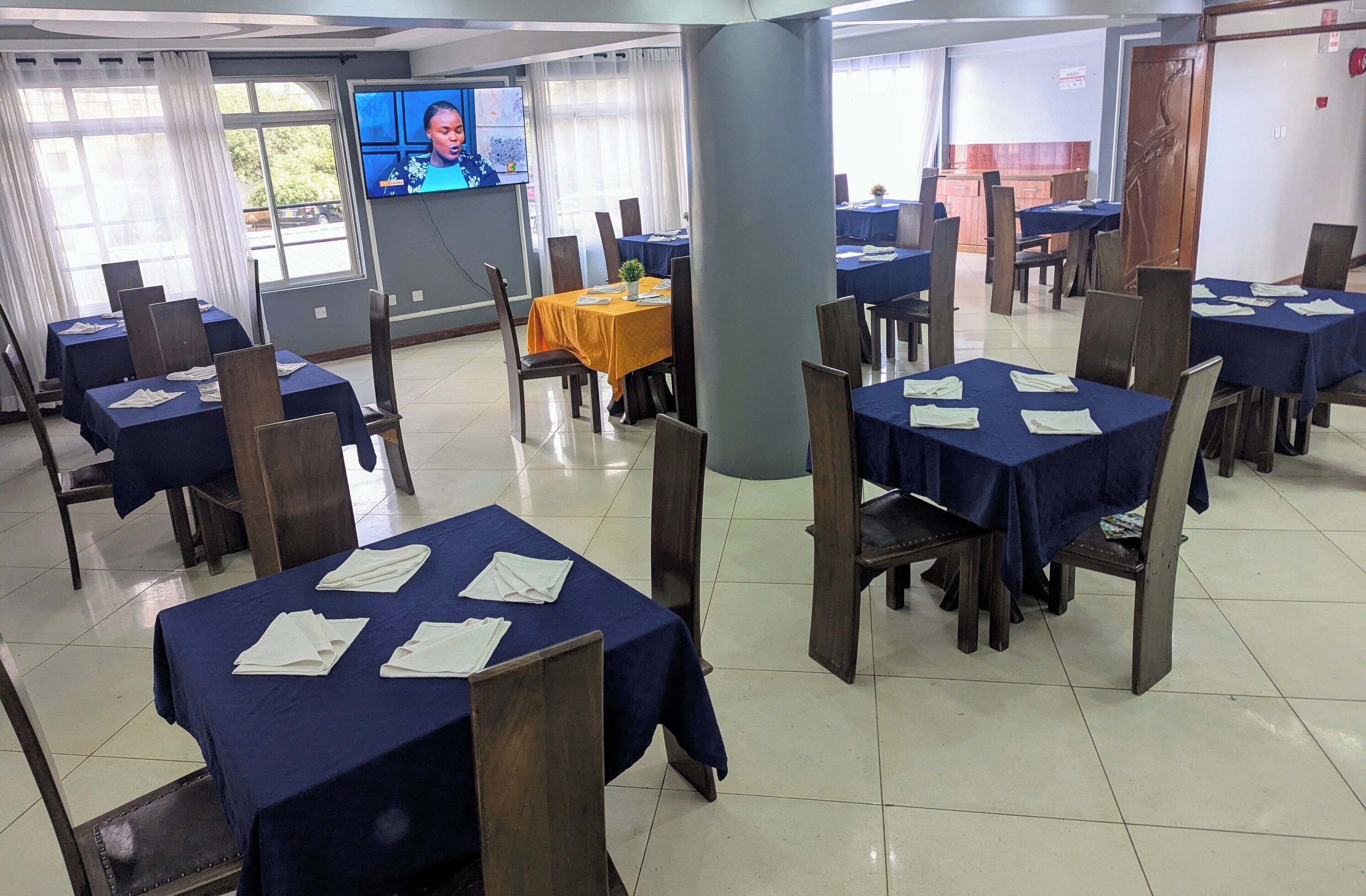 A conference room with multiple tables, chairs, and a television screen.