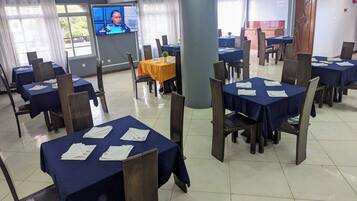 A conference room with multiple tables, chairs, and a television screen.