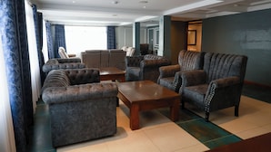 Een ruime woonkamer met een zithoek, fauteuils en een salontafel.