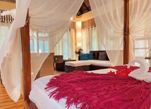 A bedroom with a canopy bed, a sitting area with a sofa and chairs, and a view of the outdoors. -  Big Bali-Style Studio with Kitchen, 3 Min to Beach (Malay)