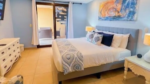 A bedroom with a bed, bedside tables, a dresser, and a painting on the wall. - Bahia Encantada G5 (Jacó)