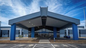 Un bâtiment moderne doté d’une entrée abritée, de grandes fenêtres et d’un parking.