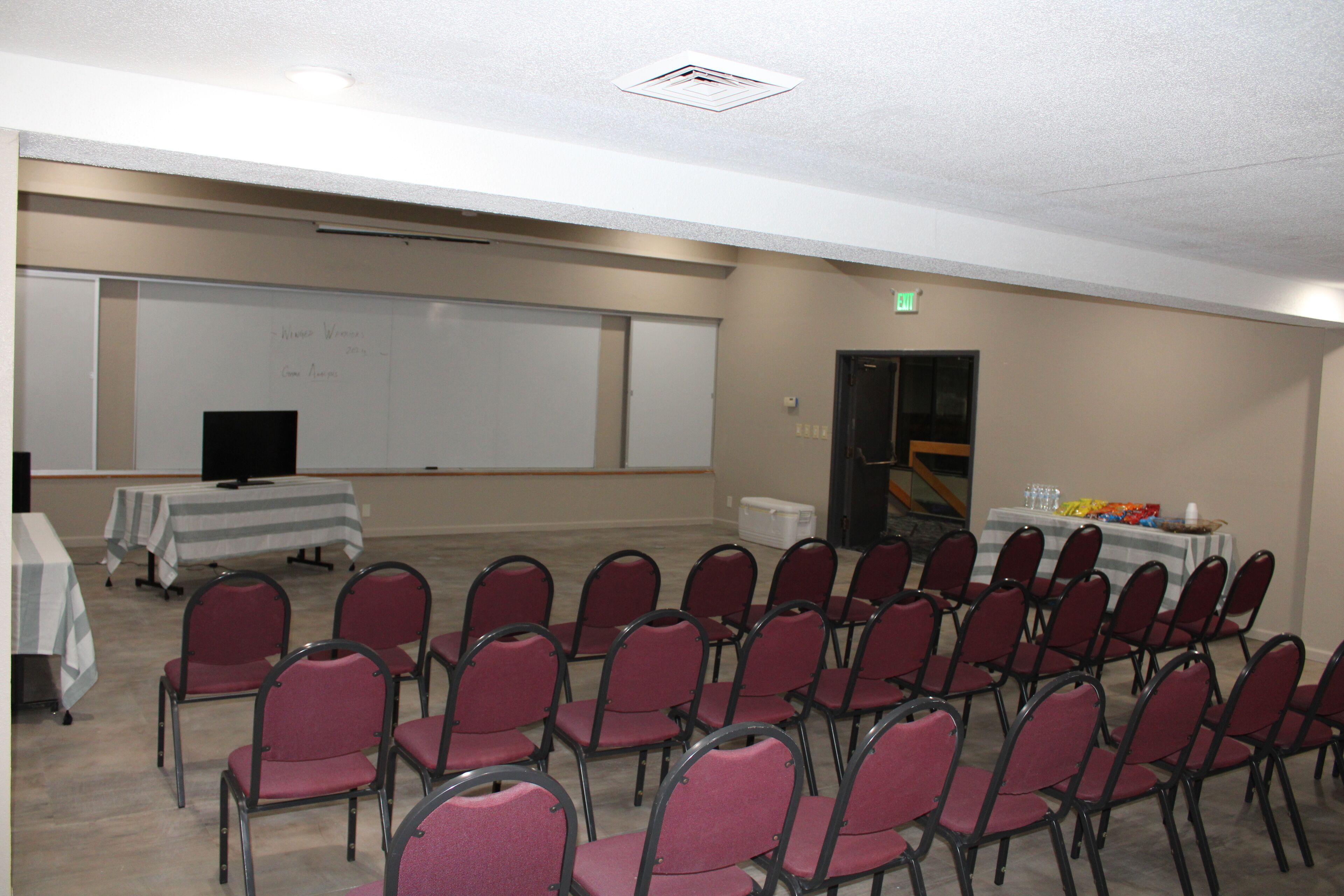 A conference room with rows of chairs, a whiteboard, and tables with refreshments.