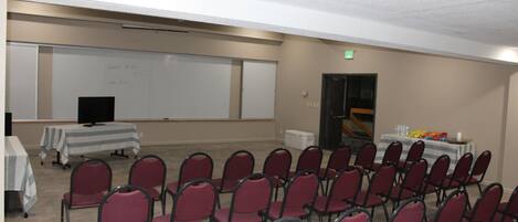 A conference room with rows of chairs, a whiteboard, and tables with refreshments.