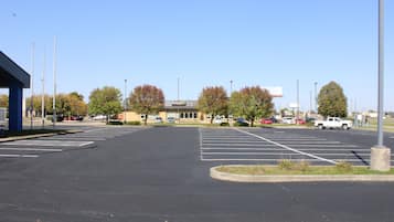 A parking lot with marked spaces, a building with a sign, and trees with autumn foliage.